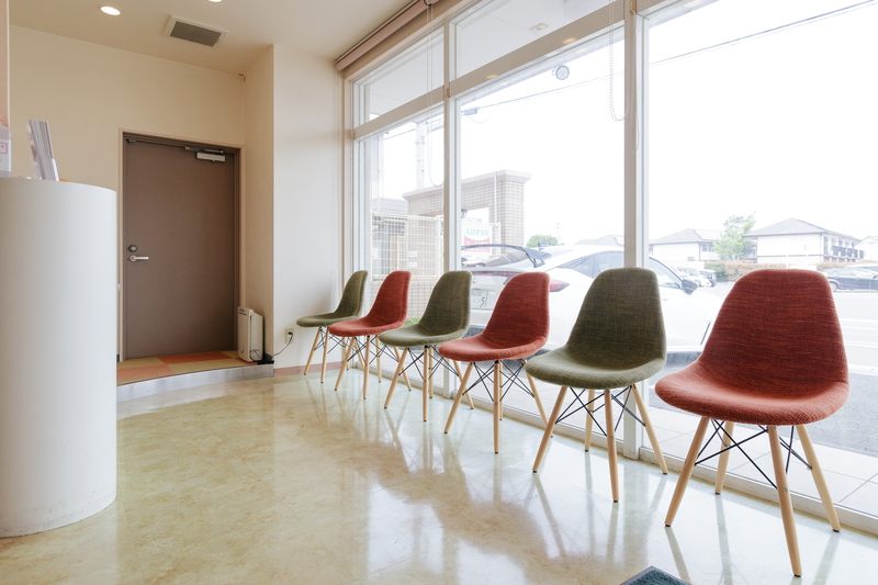 大きな窓から光が入る待合室と、色とりどりの椅子